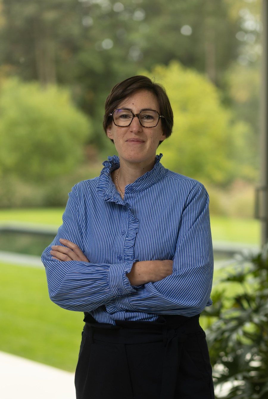Portrait de la première associée, bras croisés, devant un jardin